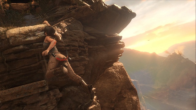 Lara Croft wisząca na jednej ręce na skałach w Syrii.
